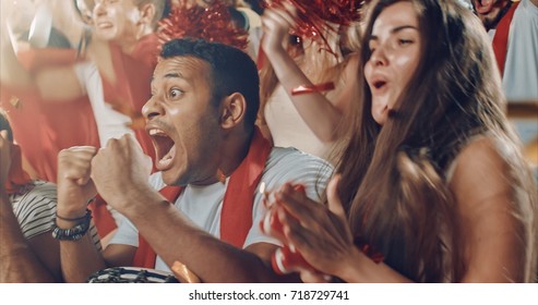 Group Of Fans Cheer For Their Team Victory On A Stadium Bleachers. They Wear Casual Fan Clothes.