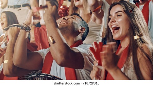 Group of fans cheer for their team victory on a stadium bleachers. They wear casual fan clothes. - Shutterstock ID 718729813