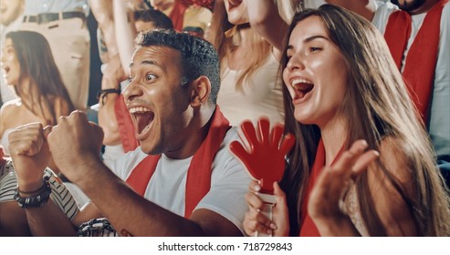 Group Of Fans Cheer For Their Team Victory On A Stadium Bleachers. They Wear Casual Fan Clothes.