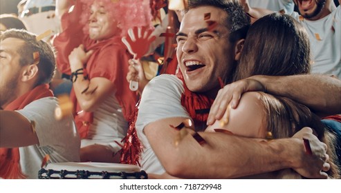 Group Of Fans Cheer For Their Team Victory On A Stadium Bleachers. They Wear Casual Fan Clothes.