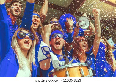 Group Of Fans Dressed In Blue Color Watching A Sports Event In The Stands Of A Stadium