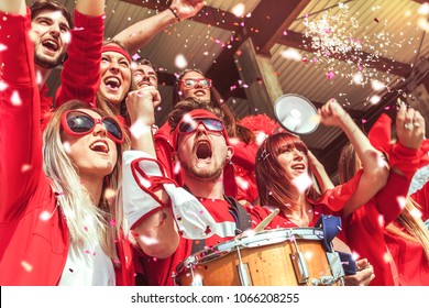 Group Of Fans Dressed In Red Color Watching A Sports Event In The Stands Of A Stadium