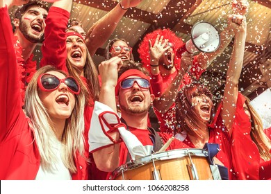 Group Of Fans Dressed In Red Color Watching A Sports Event In The Stands Of A Stadium