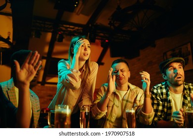 Group Of Fans Feeling Disappointed While Watching A Sports Game On TV In A Bar. 