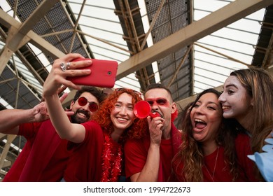 Group of fans take selfie while cheering for their sports team from a stadium. Cheerful male and female fans taking selfie while watching the game at the stadium.