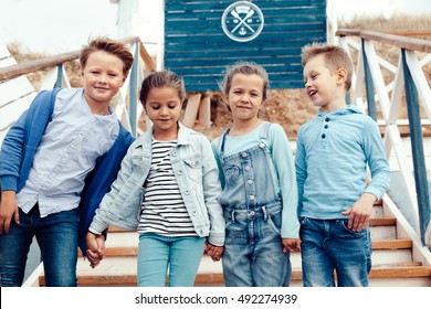Group of fashion children wearing denim clothing having fun on the sea shore. Autumn casual outfit in blue and navy color. 7-8 years old models.