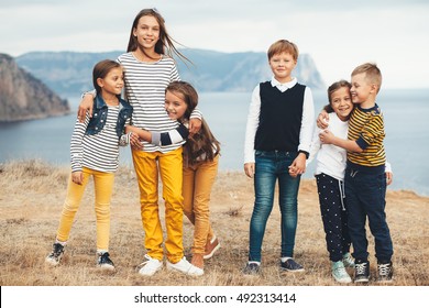 Group Of Fashion Children Wearing Same Style Clothing Hugging In The Autumn Field. Fall Casual Outfit In Navy And Yellow Colors. 7-8, 8-9, 9-10 Years Old Models.