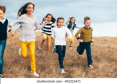 Group of fashion children wearing same style clothing running in the autumn field. Fall casual outfit in navy and yellow colors. 7-8, 8-9, 9-10 years old models.