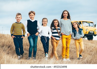 Group Of Fashion Children Wearing Same Style Clothing Having Fun In The Autumn Field. Fall Casual Outfit In Navy And Yellow Colors. 7-8, 8-9, 9-10 Years Old Models.