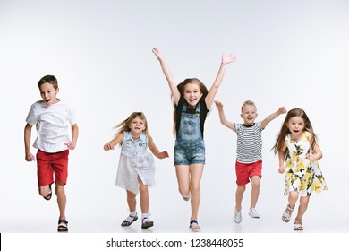 Group Of Fashion Cute Preschooler Kids Friends Running Together And Looking At Camera On A White Studio Background. The Friendship, Fashion, Summer Concept. Space For Text.