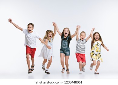 Group Of Fashion Cute Preschooler Kids Friends Running Together And Looking At Camera On A White Studio Background. The Friendship, Fashion, Summer Concept. Sublings Day.