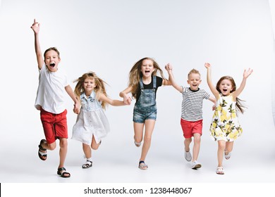 Group Of Fashion Cute Preschooler Kids Friends Running Together And Looking At Camera On A White Studio Background. The Friendship, Fashion, Summer Concept. Space For Text.