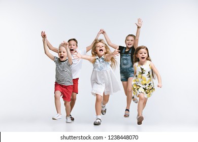 Group Of Fashion Cute Preschooler Kids Friends Running Together And Looking At Camera On A White Studio Background. The Friendship, Fashion, Summer Concept. Space For Text.