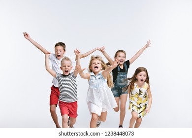 Group Of Fashion Cute Preschooler Kids Friends Running Together And Looking At Camera On A White Studio Background. The Friendship, Fashion, Summer Concept. Space For Text.