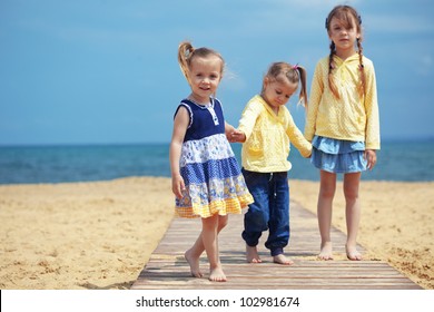 Group Of Fashion Kids Dressed In Same Clothes Playing At The Beach