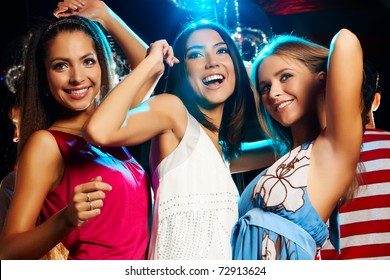 Group Of Fashionable Girls Dancing Energetically In Night Club