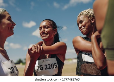 Group Of Female Athletes Stretching Arms On A Running Track. Women Runners Doing Warmup Exercises At The Stadium.