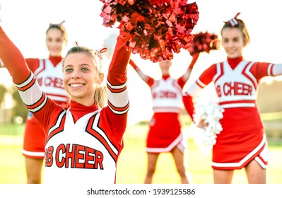 Group of female cheerleaders performing outdoors at university campus - Sport concept of cheerleading team training at high school during sunset - Warm backlight filter with focus on left girl eyes - Shutterstock ID 1939125586