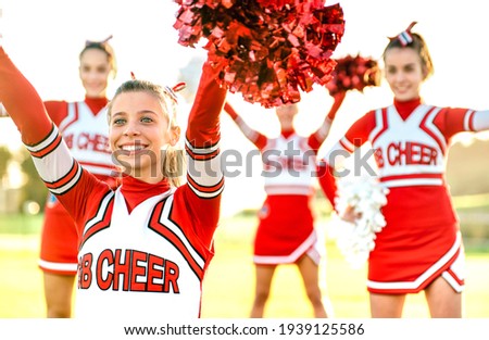 Group of female cheerleaders performing outdoors at university campus - Sport concept of cheerleading team training at high school during sunset - Warm backlight filter with focus on left girl eyes