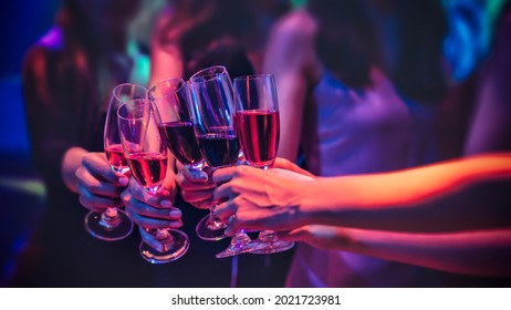 Group of female friends cheering with red wine in nightclub - Happy people drinking and having fun in nightclub - Party and nightlife concept - Focus on close up wine glass - Shutterstock ID 2021723981