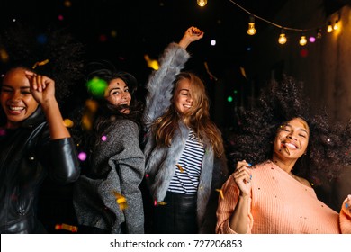 Group Of Female Friends Dancing At Night Under Confetti