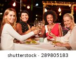 Group of female friends eating dinner at rooftop restaurant