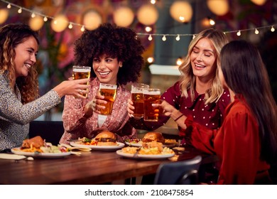 Group Of Female Friends Enjoying Night Out Eating Meal And Drinking In Restaurant