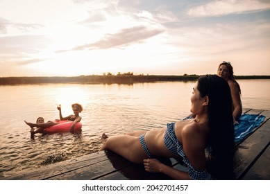 Group Of Female Friends Enjoying A Summer Day Swimming At The Lake.