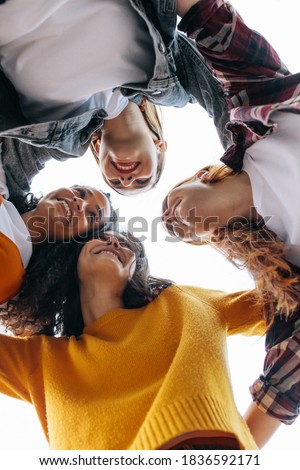 Group of female friends in a huddle. Low angle view of cheerful females enjoying outdoors.