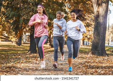 Group Of Female Friends Jogging At The City Park.Autumn Season.