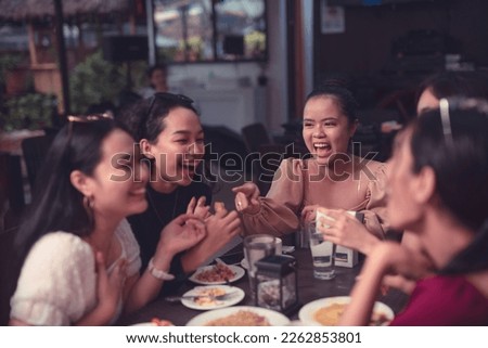 A group of female friends laugh and point at each other as they reminisce the good old days over a delicious dinner at an al fresco restaurant. Night life with friends.