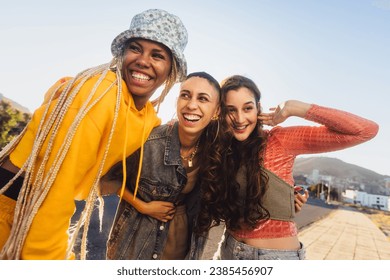 Group of female friends laughing together outdoors. Cheerful female youngsters having fun while standing together in the city. Group of generation z friends making happy memories together. - Powered by Shutterstock