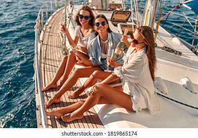 Group of female friends relaxing on luxury yacht. Having fun together and drinking champagne while sailing in the sea. Traveling and yachting concept.