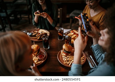 Group of female friends taking photos of food in the restaurant before eating. People and social media concept