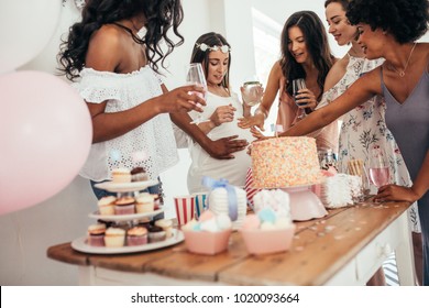 Group Of Female Friends Touching Tummy Of A Pregnant Woman At A Baby Shower. Female Friends Sharing Love And Support To Pregnant Woman.