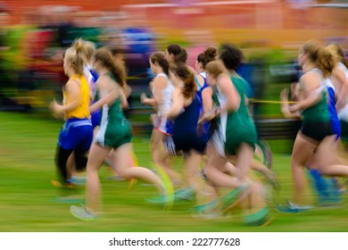 Group Of Female High School Athletes Running A Cross Country Race.