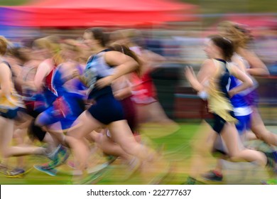 Group Of Female High School Athletes Running A Cross Country Race.