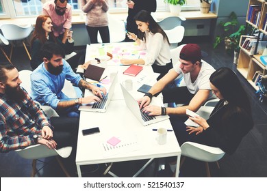 Group Of Female And Male IT Professionals Working On Software Development Using Modern Devices While Sitting At Table. Skilled Bloggers Are Copywriting For Media Web Page Typing On Computer Keyboard