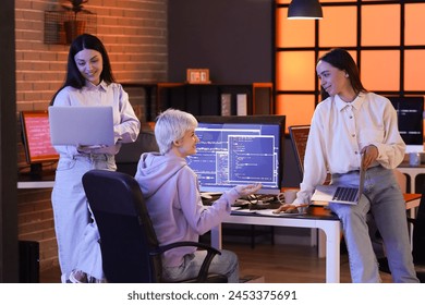 Group of female programmers with laptops working in office at night