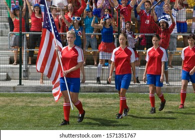 Group of female soccer players with American Flag walking on field - Powered by Shutterstock