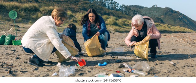 Group Of Female Volunteers Picking Up Trash On The Beach