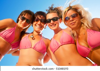 a group of females in bikinis together on the beach with sunglasses