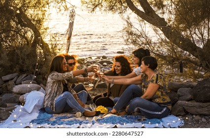 Group of females young middle age friends celebrate all together sitting at the natural rocks beach and drinking wine toasting and smiling. Friendship and summer holiday vacation women people - Powered by Shutterstock