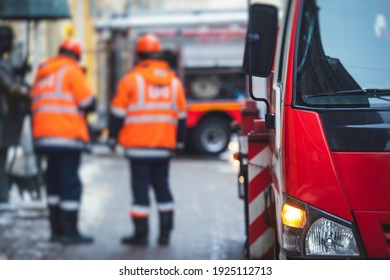 Group of fire men in uniform during fire fighting operation in the city streets, firefighters with the fire engine truck fighting vehicle in the background, emergency and rescue