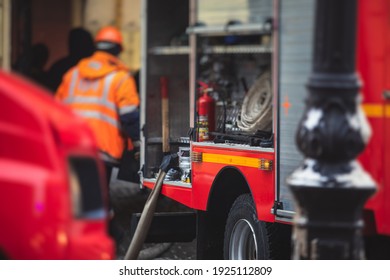 Gruppe von Feuerwehrmännern in Uniform während der Brandbekämpfung in den Straßen der Stadt, Feuerwehrmänner mit dem Feuerwehrfahrzeug im Hintergrund, Notfall- und Rettungsfahrzeug