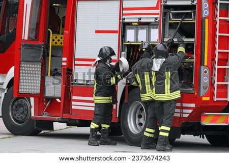group of firefighters in action with the fire truck during the emergency with uniform and protective helmet