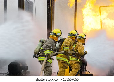 Group Of Firefighters Advance Forward Putting Out A Fire.