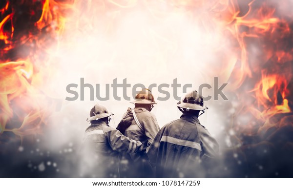 Group of firefighters fighting a fire, They are in\
the midst of fire and\
smoke.