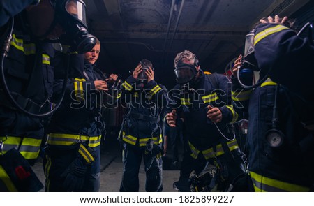 Group of firefighters standing inside the fire brigade wearing helmet and protective uniform