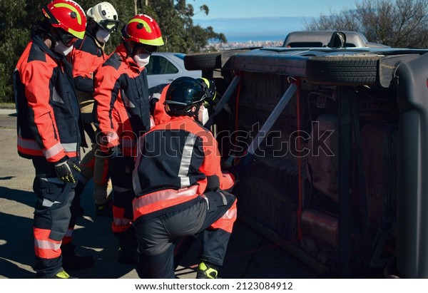 Group of firefighters wearing uniforms and\
helmets carry out a rescue in a car\
accident